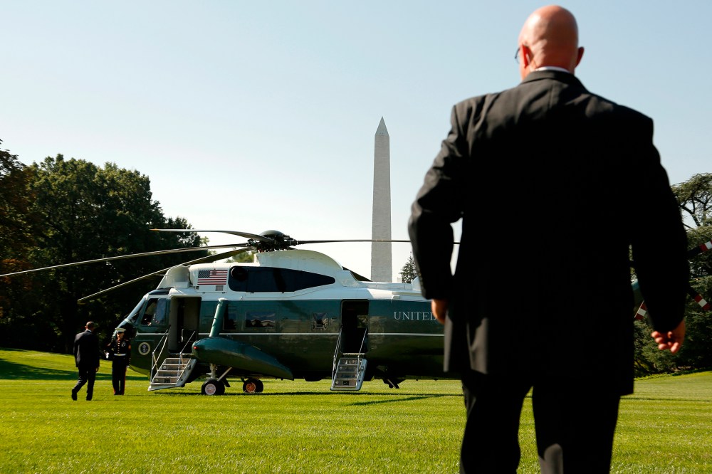 A Secret Service agent watches as U.S. President Barack Obama boards the Marine One helicopter, Aug. 26, 2014.