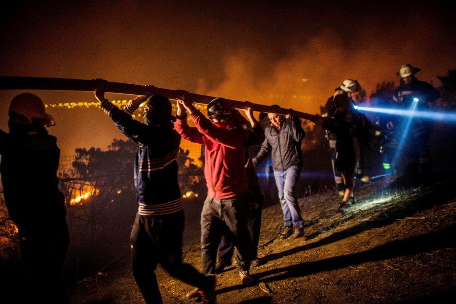 Locals help firefighters working to put out a forest fire in the hills of Valparaiso, Chile, March 14, 2015. Thousands of people were evacuated from around Valparaiso on Friday as a forest fire raged out of control. (Photo by Pablo Sanhueza/Reuters)