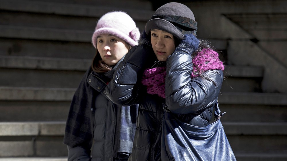 People walk through the wind and cold on Wall Street in New York's financial district March 19, 2015. (Photo by Brendan McDermid/Reuters)