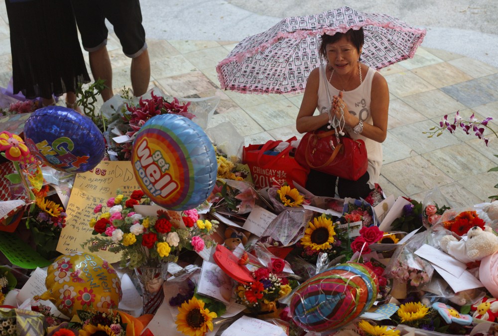 A woman weeps as she prays in the rain at a well-wishing corner for Singapore's former Prime Minister Lee Kuan Yew at the Singapore General Hospital March 22, 2015. (Photo by Edgar Su/Reuters)