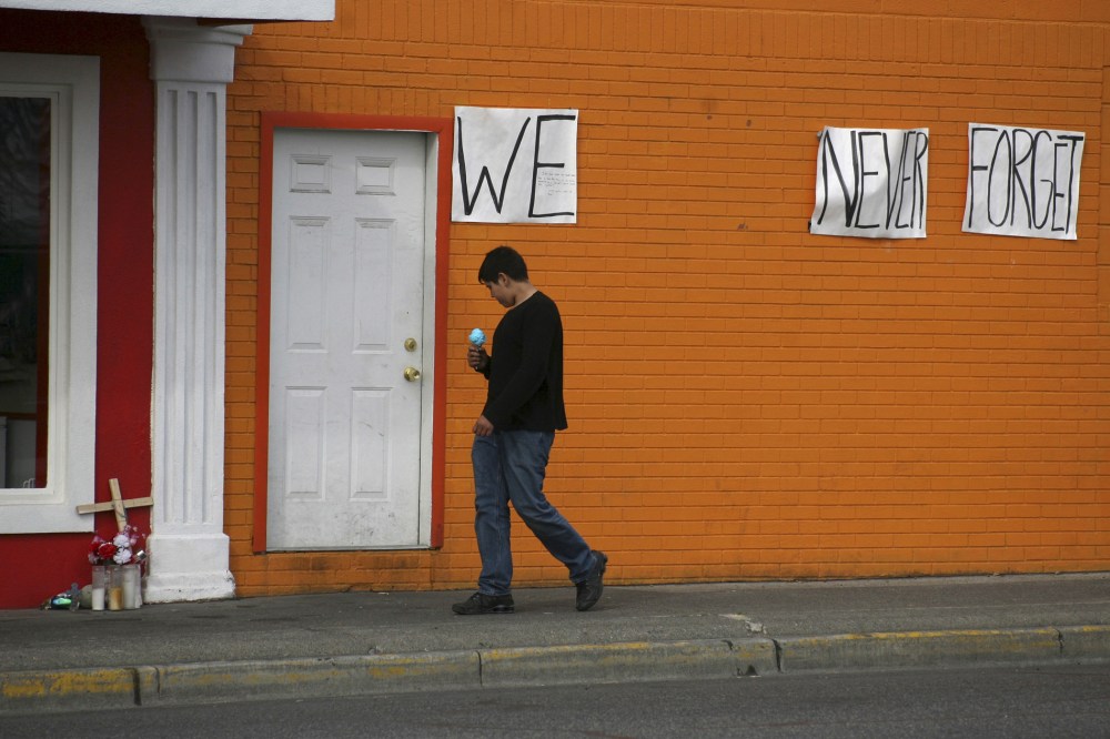 A boy with an ice-cream cone walks past a memorial to Antonio Zambrano-Montes in Pasco, Washington, March 21, 2015. (Photo by Action Images/Reuters)