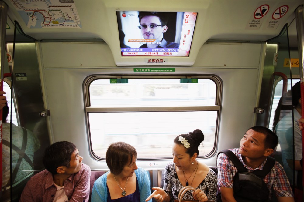 Passengers watch a television screen broadcasting news on Edward Snowden on a train in Hong Kong June 14, 2013.