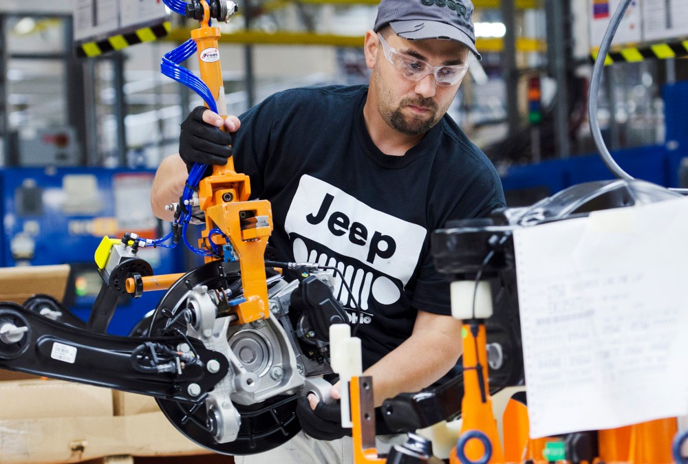 A production line worker installs a brake and rotor unit are on the rear axle assembly of a 2014 Jeep Cherokee at the Chrysler Toledo Assembly Complex in Toledo, Ohio on July 18, 2013.