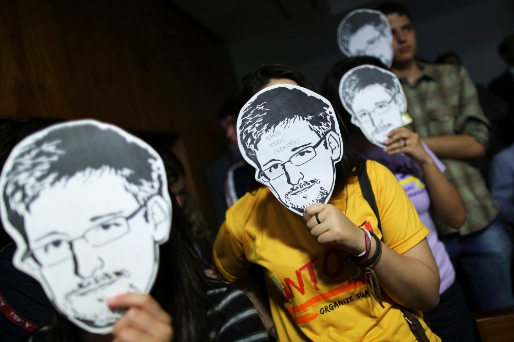 People use masks with pictures of Snowden masks during the testimonial of Greenwald before a Brazilian Congressional committee, Aug. 6, 2013.