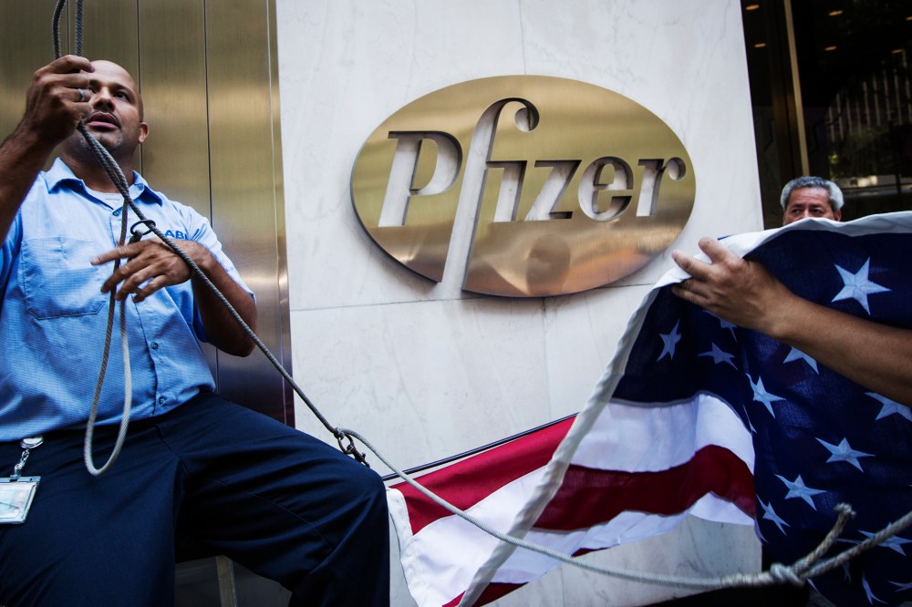 Workers raise a U.S. flag outside the Pfizer building in New York on Sept. 4, 2013.