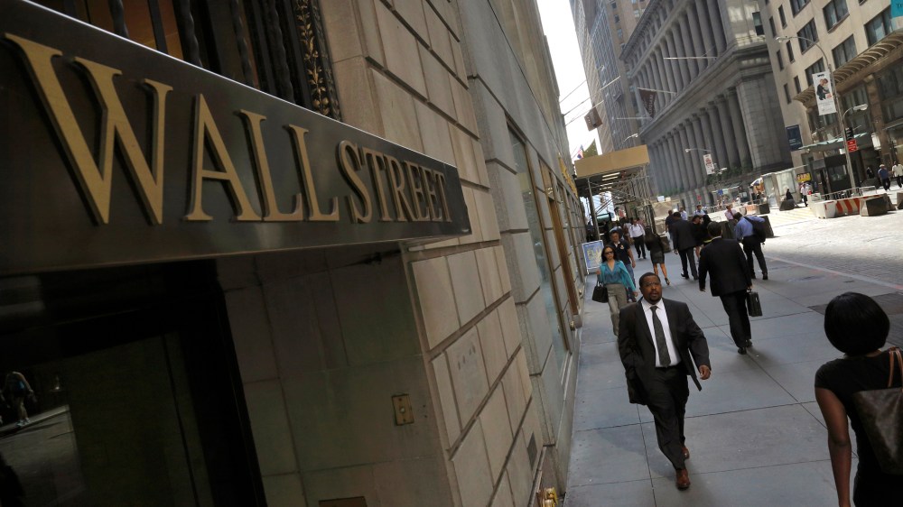 Morning commuters walk on Wall Street in New York's financial district