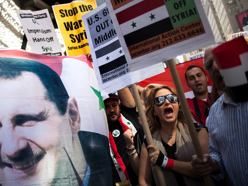 Claudia Salmeh, a Syrian born American who supports President Bashar al-Assad, chants "No More War," as fellow activists hold an image of Assad during an anti-war rally in Times Square, New York