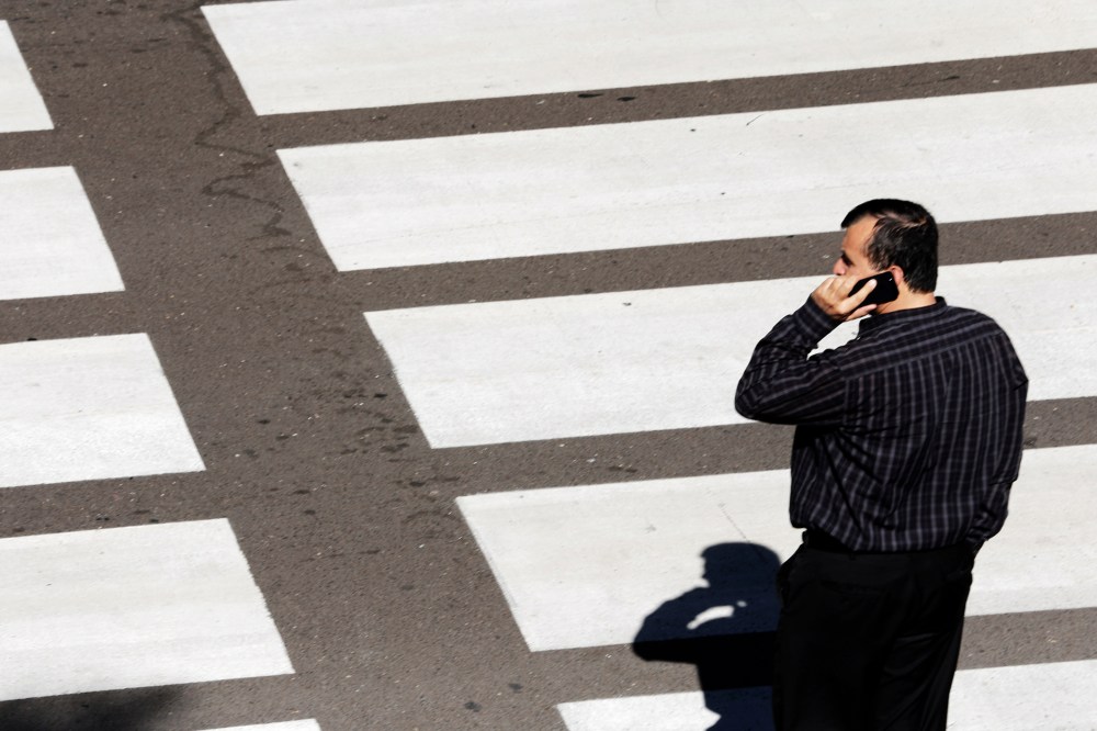 A man talks on his mobile phone as he waits at a crosswalk at Lindbergh Field Airport in San Diego