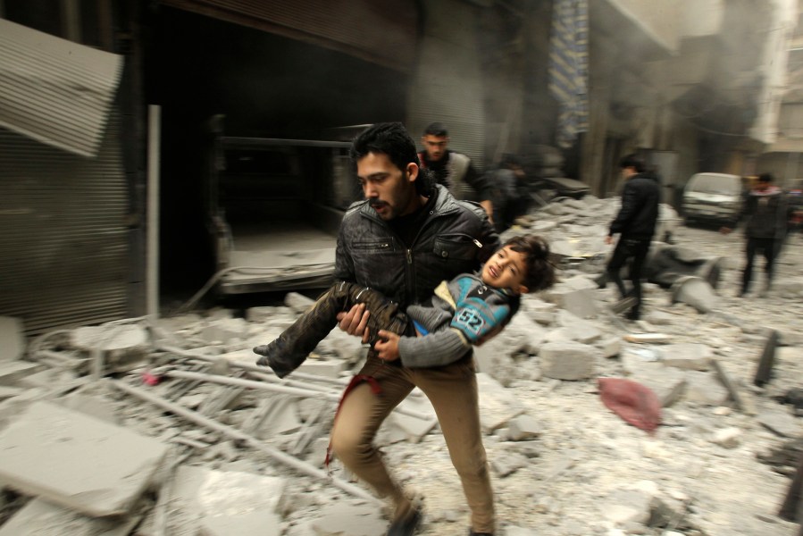 A man runs as he carries a child who survived from what activists say was an airstrike by forces loyal to Syrian President Bashar al-Assad, at al-Ferdaws in Aleppo, Jan. 21, 2014.