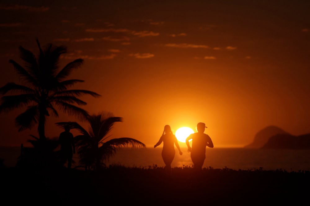 People exercise in Barra da Tijuca beach during the sunrise in Rio de Janeiro (Photo by Ricardo Moraes/Reuters)