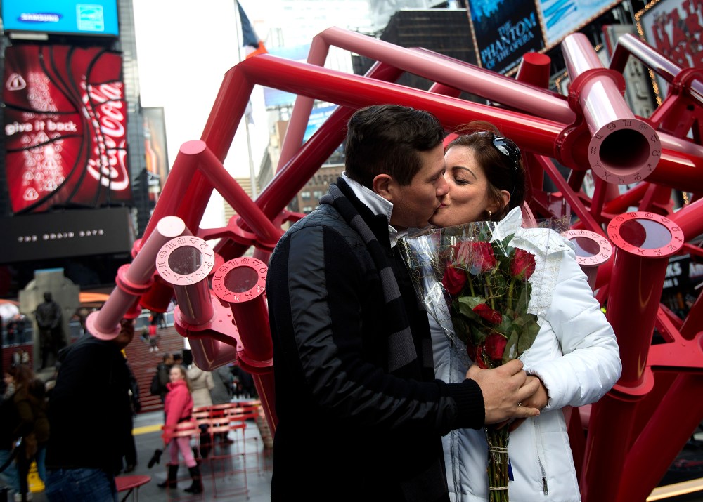 A couple, holding roses, kiss in Times Square on Valentine's Day in New York Feb. 14, 2014. (Photo by Carlo Allegri/Reuters)