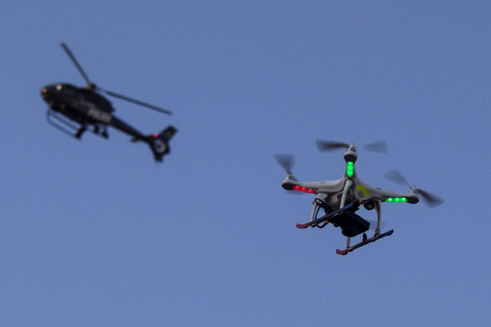 A police helicopter flies past a UAV drone Quadcopter which was flying over a post-march street celebration in west Baltimore, Md., May 2, 2015. (Photo by Adrees Latif/Reuters)