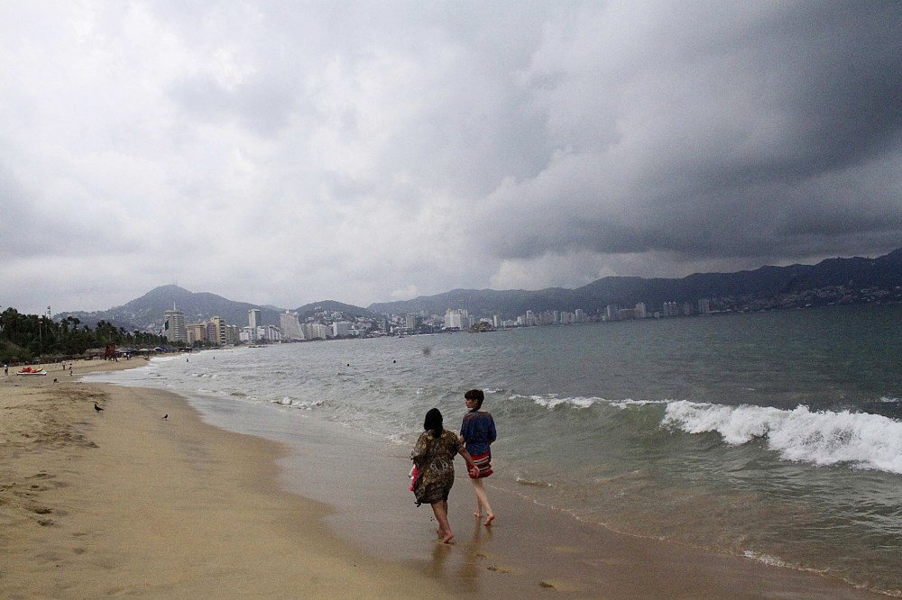 Tourists walk along a beach as dark clouds brought by hurricane Blanca are seen in Acapulco, state of Guerrero, on June 4, 2015. (Photo by Claudio Vargas/Stringer Mexico/Reuters)