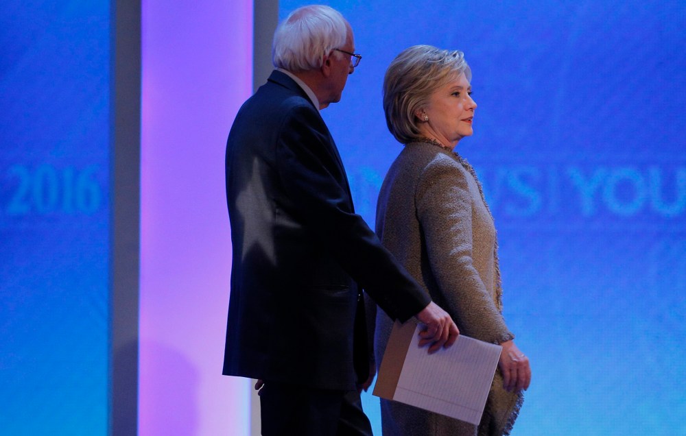 Democratic presidential candidates Bernie Sanders and Hillary Clinton talk as they return to the stage together at the end of a commercial break at presidential debate, Manchester, N.H. Dec. 19, 2015. (Photo by Brian Snyder/Reuters)