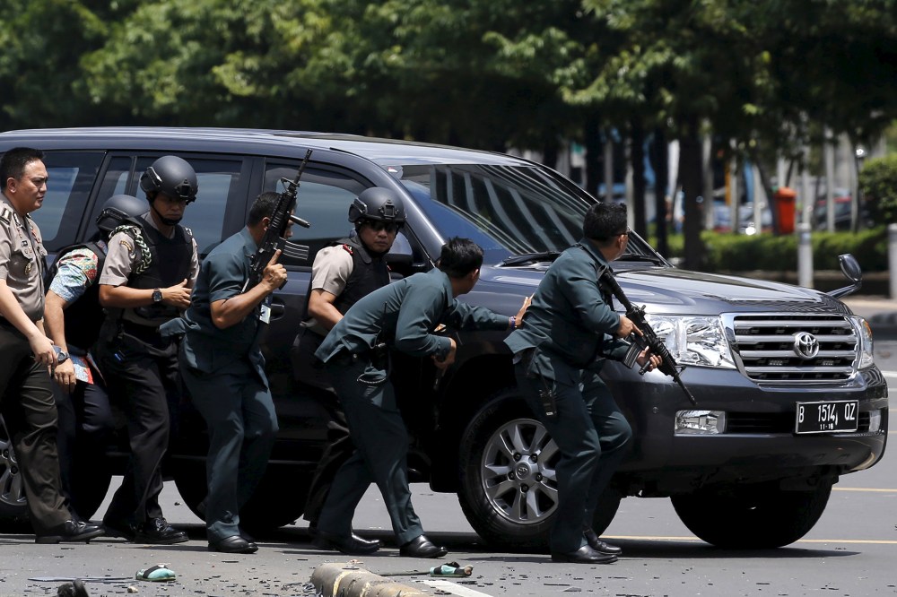 Indonesian police hold rifles while walking behind a car for protection in Jakarta on Jan. 14, 2016. (Photo by Beawiharta Beawiharta/Reuters)
