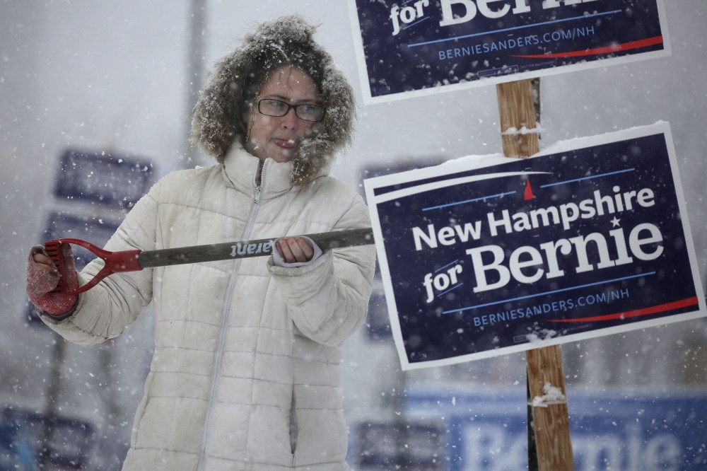 A worker uses a shovel to wipe snow off of an election sign in Manchester, N.H., Feb. 5, 2016. (Photo by Carlo Allegri/Reuters)
