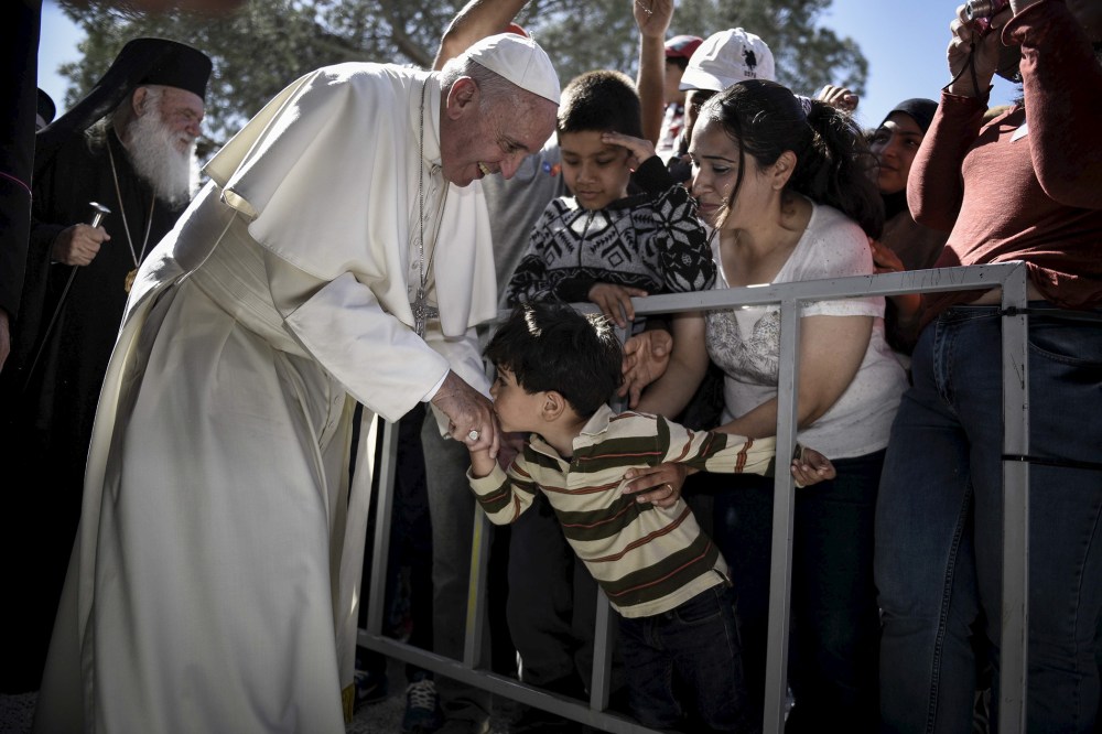 A boy shakes the hand of Pope Francis as he greets migrants and refugees at Moria refugee camp near the port of Mytilene, on the Greek island of Lesbos, April 16, 2016. (Photo by Andrea Bonetti/Greek PM Press Office/Handout/Reuters)