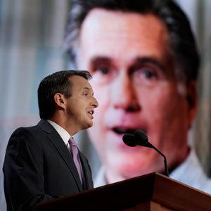 T-Paw giving a speech last month in front of a giant picture of Mitt Romney's face.