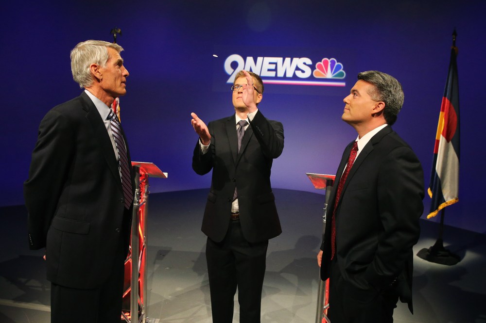 Incumbent Democratic Sen. Mark Udall, and his opponent U.S. Rep. Cory Gardner, right, watching a coin flip by moderator Brandon Rittiman to see who gets first question during their final pre-election televised debate in Denver. Colo. on Oct. 15, 2014.