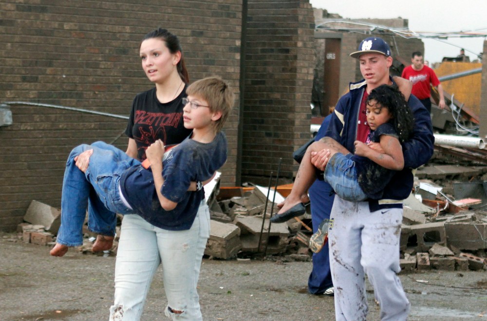 Teachers carry children away from Briarwood Elementary school after a tornado destroyed the school in south Oklahoma City, Okla, Monday, May 20, 2013. Near SW 149th and Hudson. (AP Photo/ The Oklahoman, Paul Hellstern)