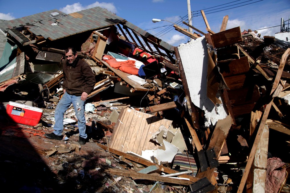 James Traina climbs over the remains of his parent's house which was destroyed by Superstorm Sandy in Staten Island, N.Y. Friday, Nov. 2, 2012. (AP Photo/Seth Wenig)