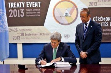 Secretary of State John Kerry signs the Arms Trade Treaty as Under Secretary-General for Legal Affairs Miguel Serpa Soares looks on.