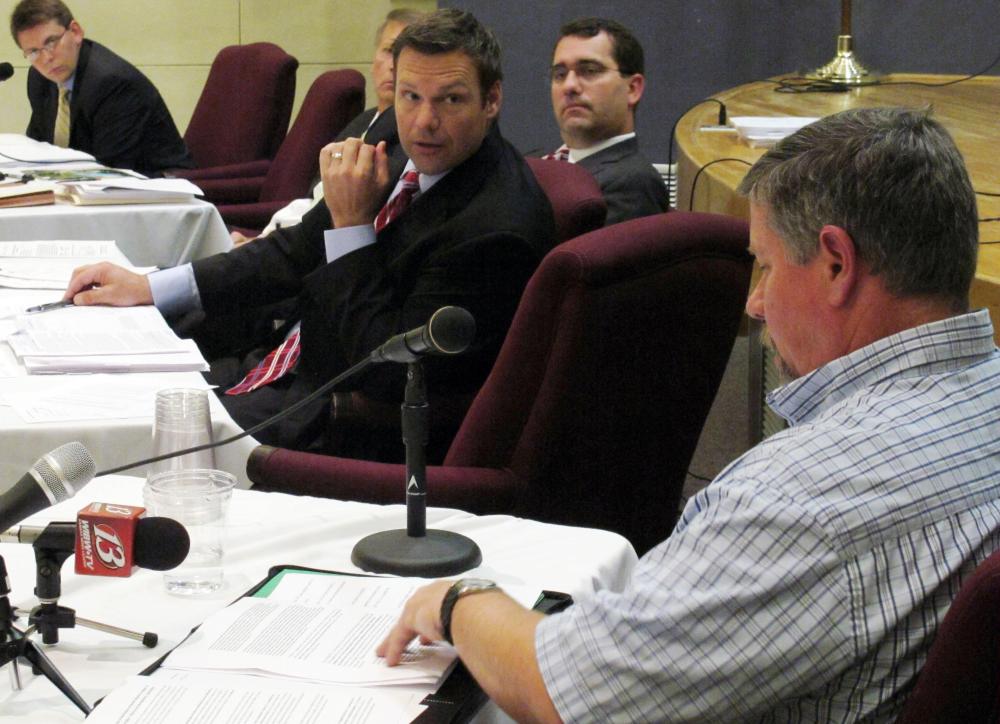 Kansas Secretary of State Kris Kobach, center, questions Joe Montgomery, lower right, a Manhattan, Kan., resident, during a meeting of the State Objections Board, Thursday, Sept. 13, 2012, in Topeka, Kan. The board includes Kobach and, behind him,...