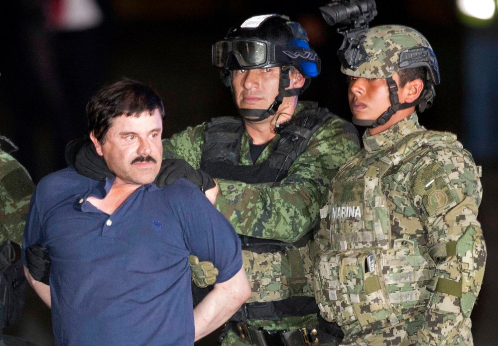 In this Friday, Jan. 8, 2016 photo, Joaquin "El Chapo" Guzman is made to face the press as he's escorted to a helicopter in handcuffs by soldiers and marines at a federal hangar in Mexico City. (Photo by Eduardo Verdugo/AP)