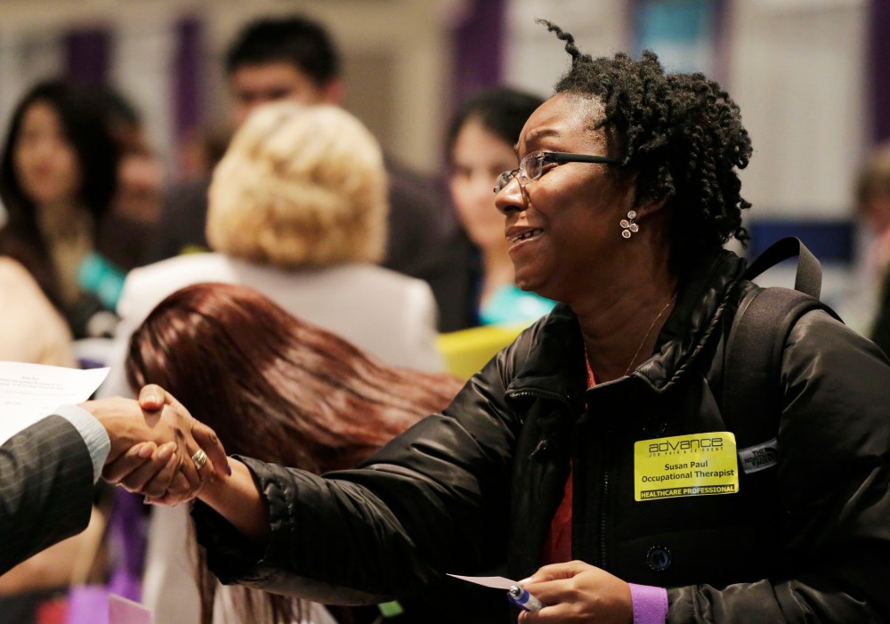Susan Paul, who has recently completed a Masters program in occupational therapy, shakes hands with a recruiter at a healthcare job fair, Thursday, March 14, 2013, in New York.   (Photo by Mark Lennihan/AP)