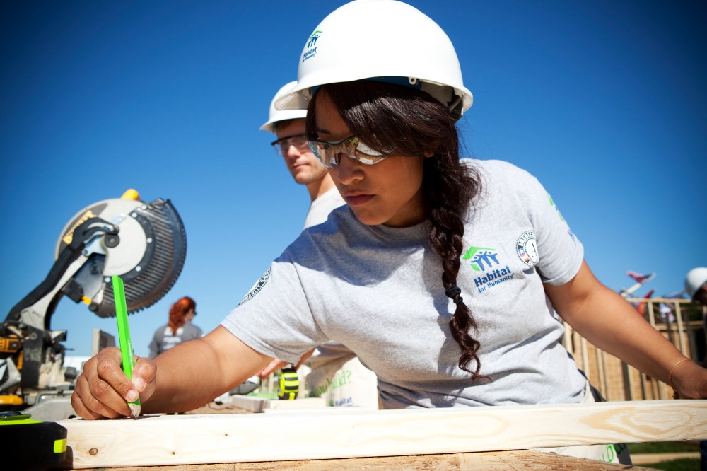 AmeriCorps volunteer Victoria Piar from Habitat for Humanity of Orange County, saws lumber for a new house frame.