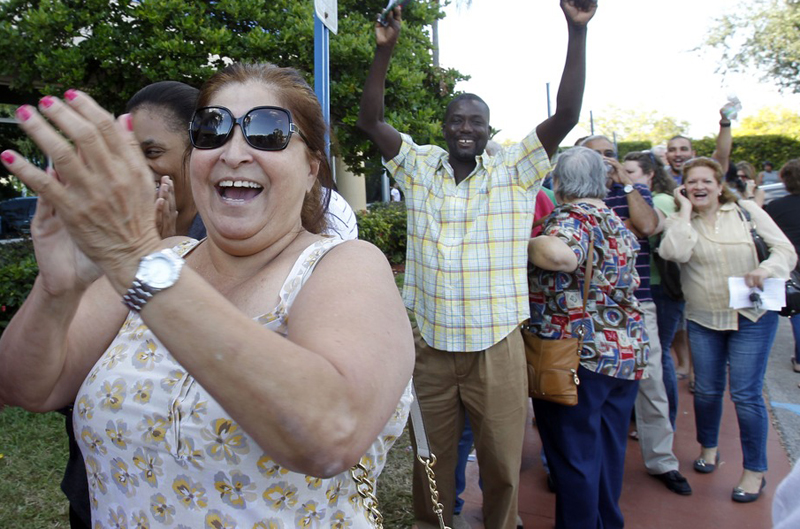 Myrna Peralta, left, and other voters react after the elections office in Miami-Dade County reopened its doors to voters who waited in long lines for an absentee ballot in Doral, Fla., Sunday, Nov. 4. The doors were closed after election officials were...