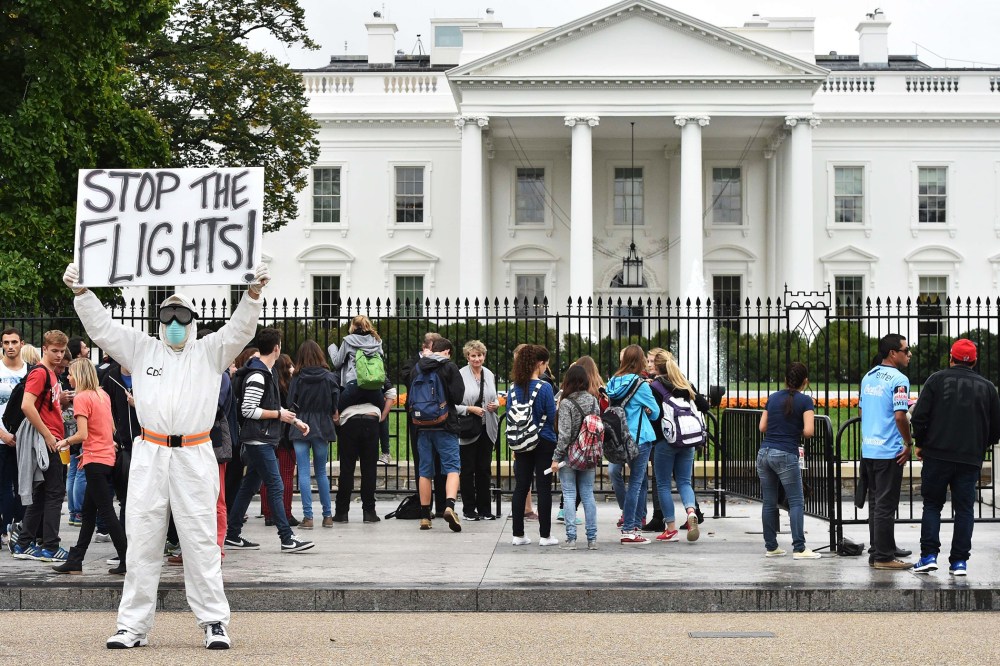 Jeff Hulbert from Annapolis, Md., dressed in a protective suit and mask, holds a poster demanding for a halt of all flights from West Africa as he protests outside the White House in Washington, D.C. on Oct. 16, 2014.