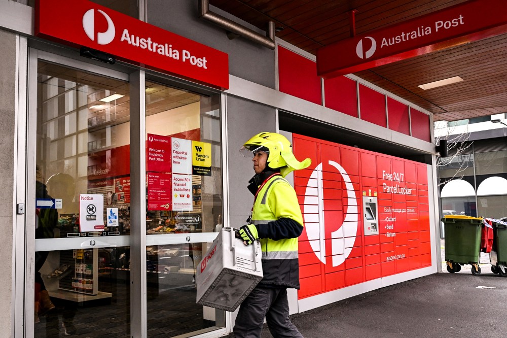 Image: A postman enters an Australia Post store
