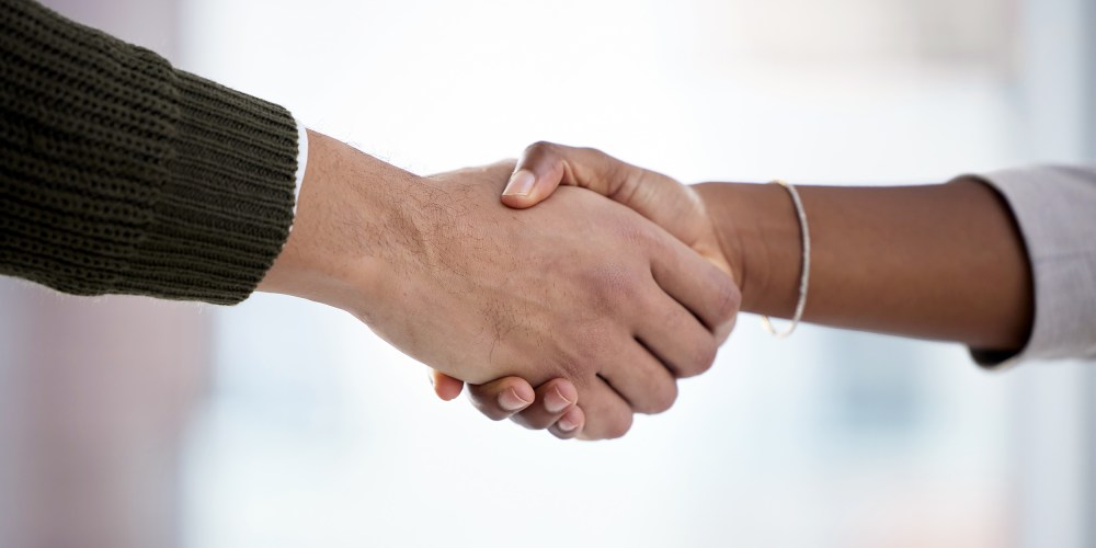 Closeup shot of two businesspeople shaking hands in an office.