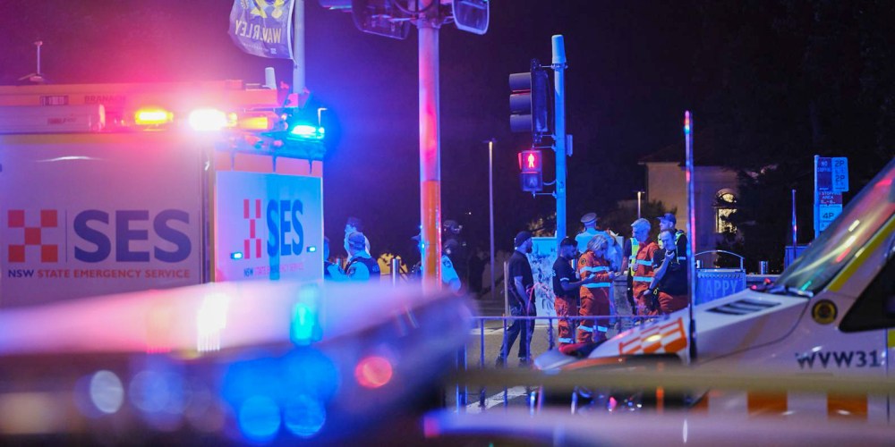 Emergency responders at Sydney’s Bondi Beach confer amid the flashing lights of EMS vehicles.