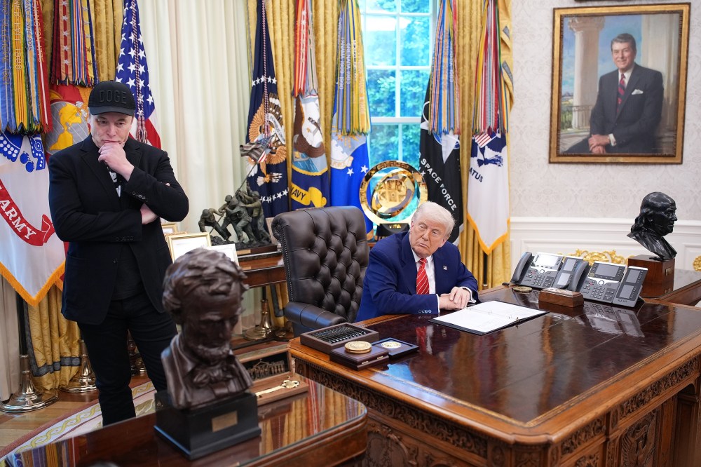 Tesla CEO Elon Musk and U.S. President Donald Trump listen to a question from reporters in the Oval Office.