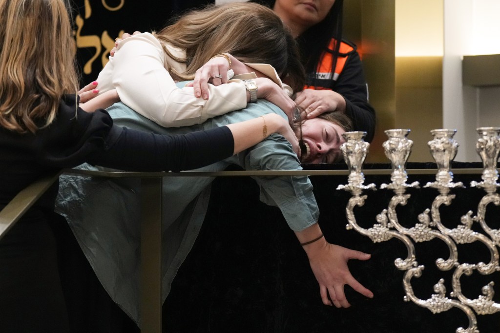 People cry beside a coffin.