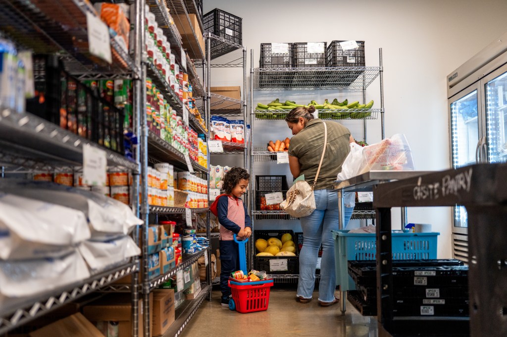 A woman and child gather food in a community pantry.
