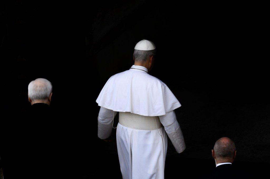 Pope Leo XIV in white and two others in black with their backs to the camera.