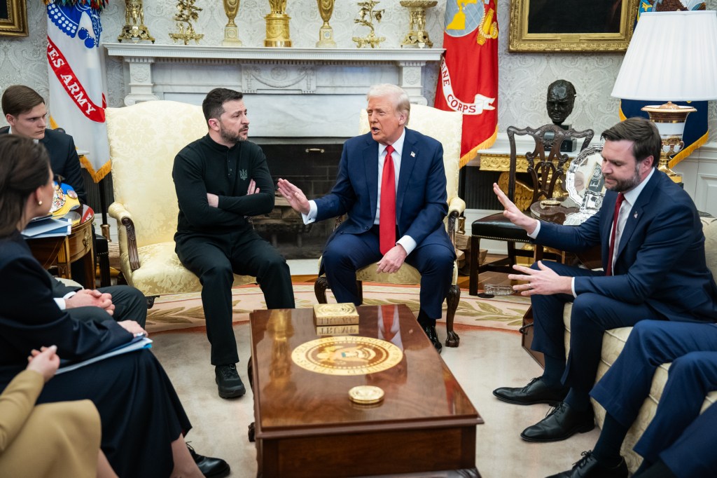 Ukrainian President Volodymyr Zelenskyy with his arms crossed sits next to President Donald Trump and Vice President JD Vance, both with their hands out, in the Oval Office.