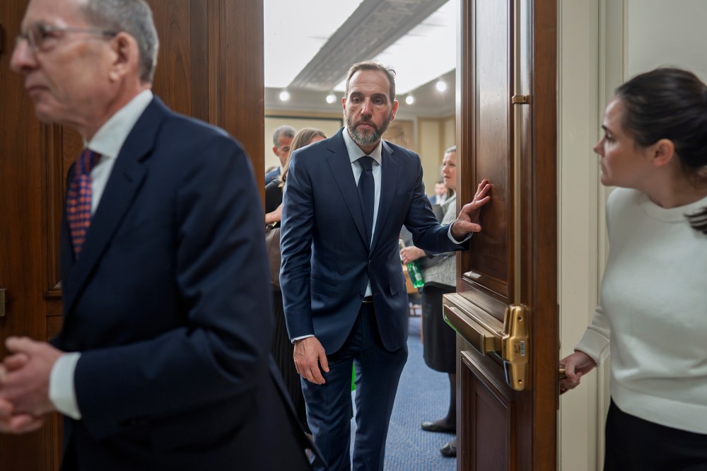 Former Department of Justice Special Counsel Jack Smith, center, walks out of a room.