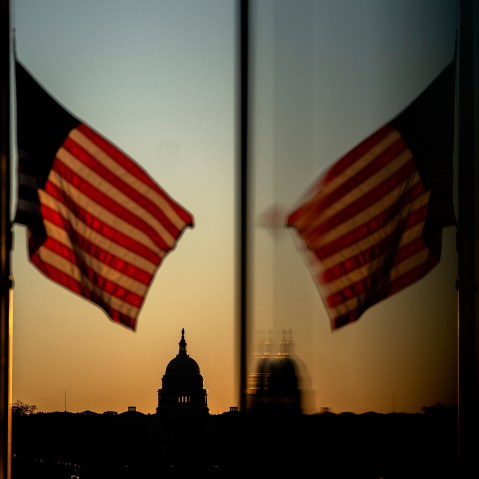 At sunset, an American flag flies in the foreground with the Capitol in focus in the background.