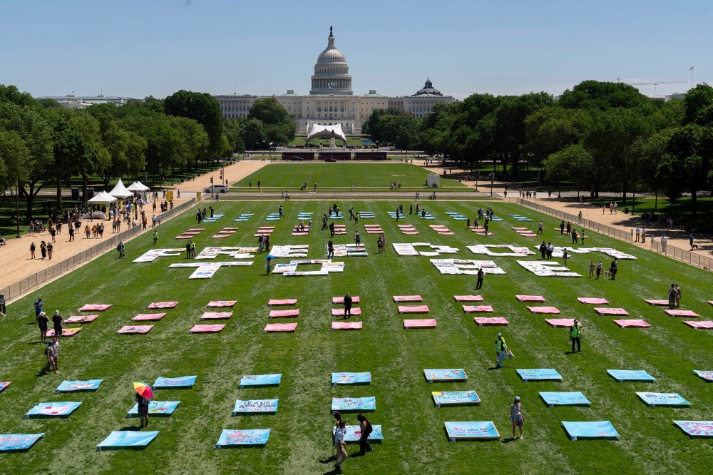 Pink, blue, and white quilt panels rest on the grass of the National Mall.
