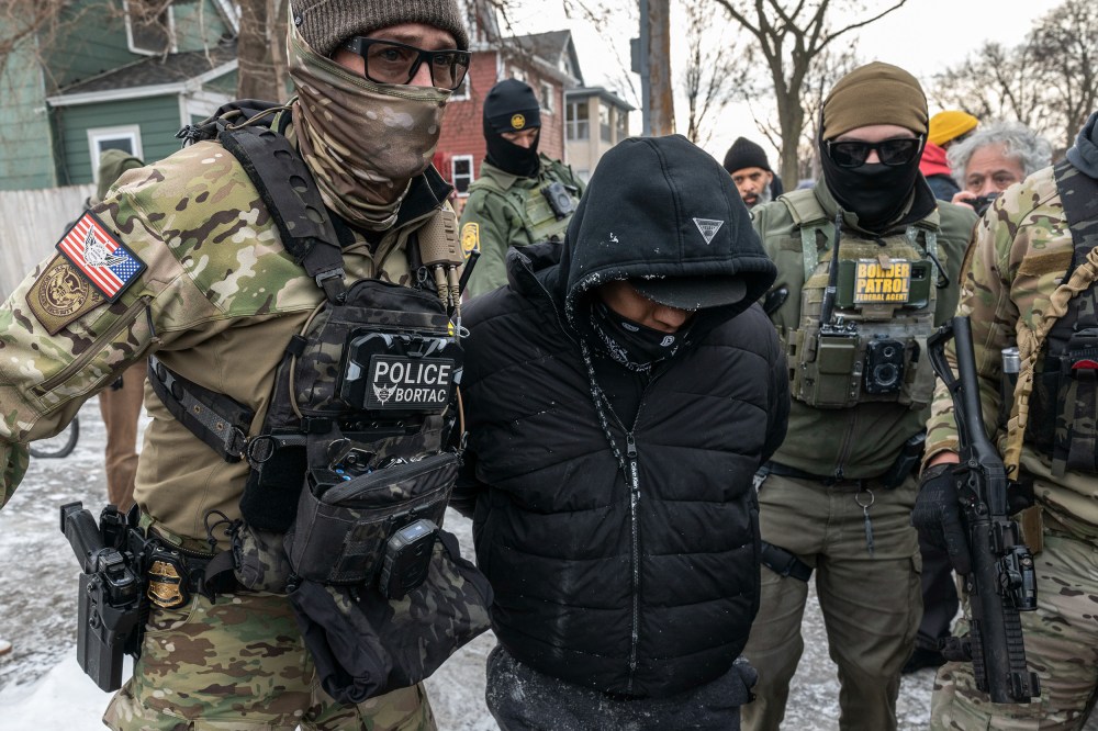 Federal agents wearing body cams detain a person.