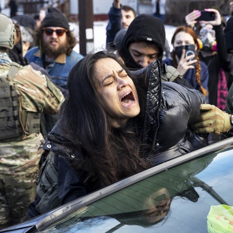Federal Agents arrest a woman after smashing her car windows for allegedly blocking the street during an immigration enforcement operation on Jan. 13, 2026, in Minneapolis.
