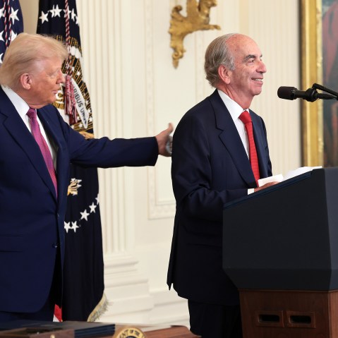 President Donald Trump pats the back of John Hess as he delivers remarks on June 12, 2025 in the East Room of the White House.