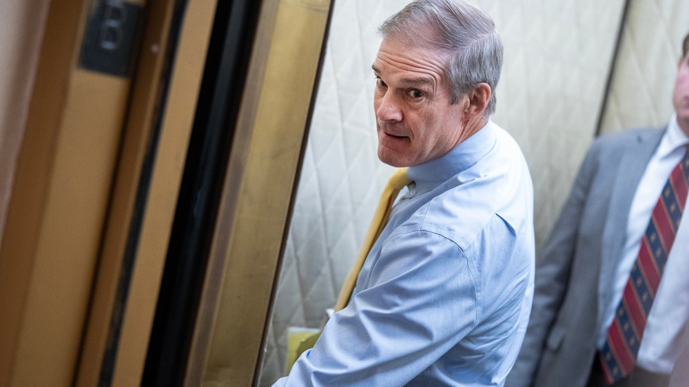 Rep. Jim Jordan pressing a button in the elevator while a young man stands behind him.