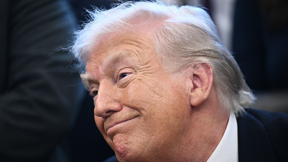 A tight photo of President Trump shows his face with a smirk on.