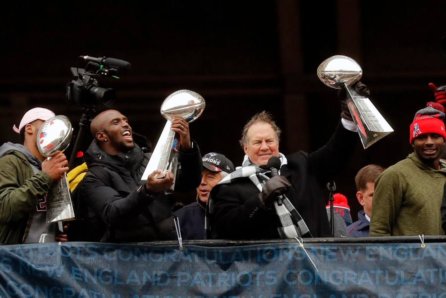 Bill Belichick and several Patriots raise the super bowl trophies during celebration parade.