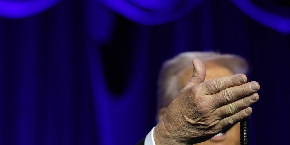 Donanld Trump's right hand obscures his face as he speaks at the National Prayer.
